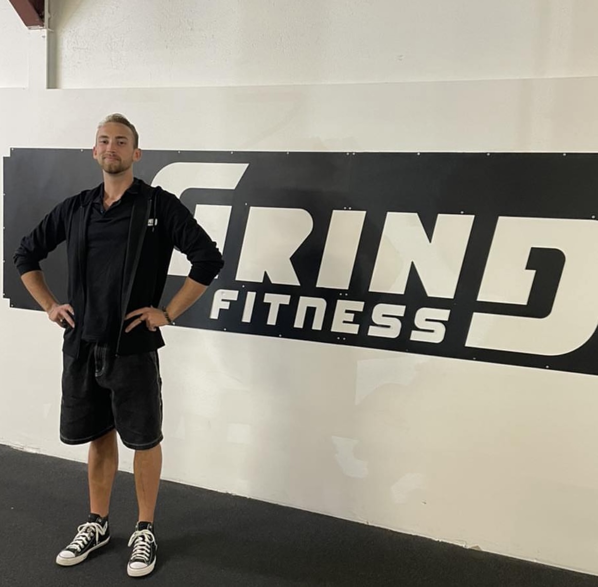 Coach certifié de Grind Fitness montrant des exercices de musculation dans la salle de sport.